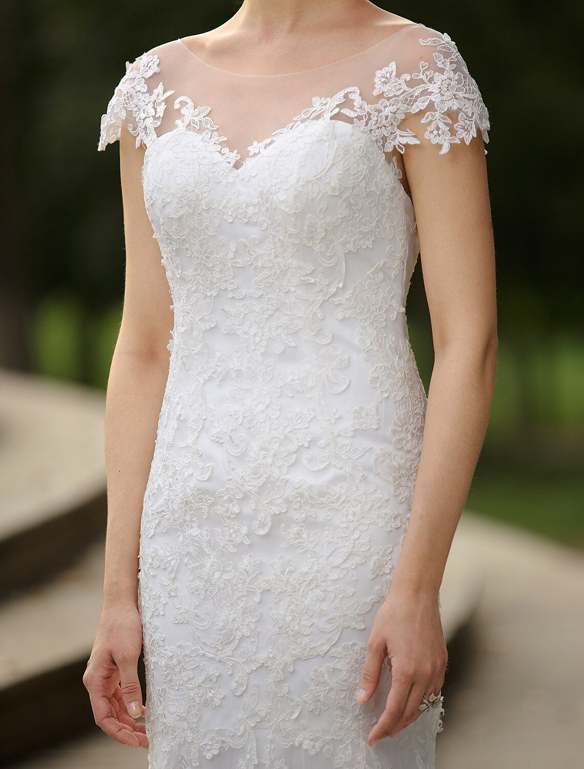 Close-up of illusion neckline and short sleeve details on bridal gown.