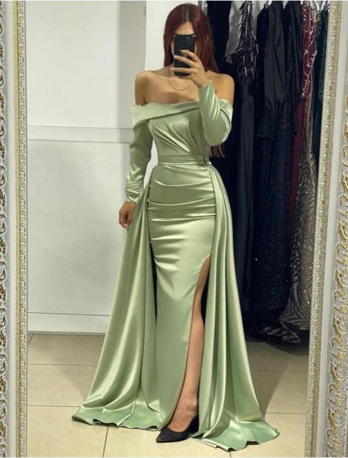 Woman in black mermaid trumpet gown with deep V-neck and high slit.