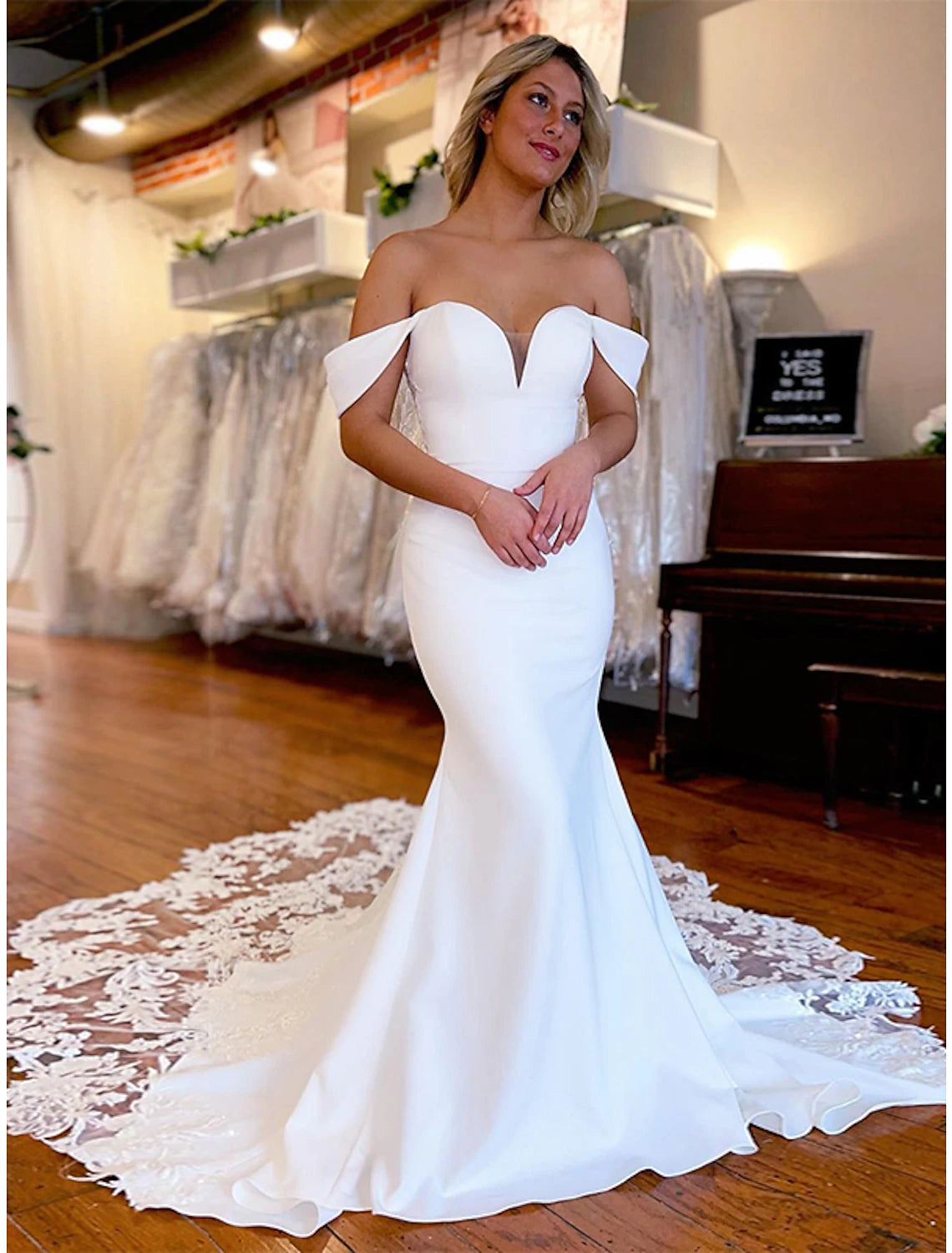Elegant mermaid trumpet bridal gown with off-shoulder neckline and appliques.