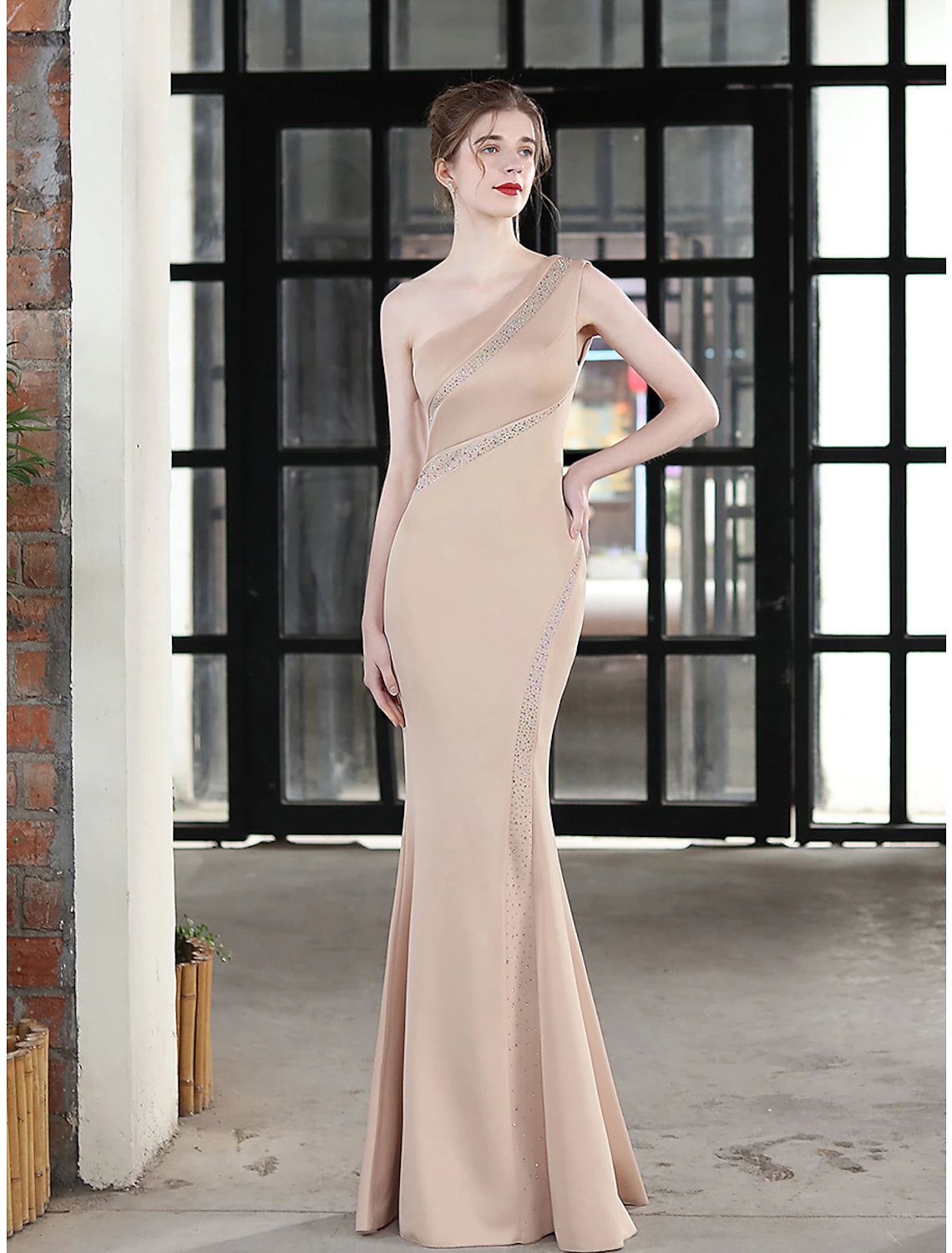 Side profile of a woman wearing a sparkling one-shoulder gown.