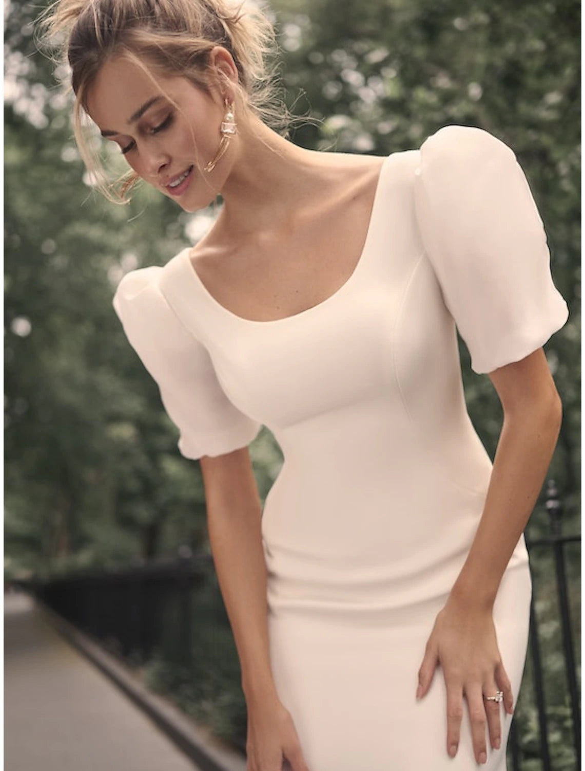 Back view of a white satin bridal gown, highlighting the court train and scoop neck.