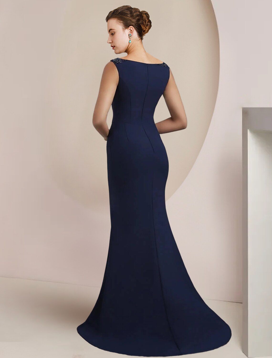Side view of a woman wearing a sleeveless chiffon formal gown with a sweep train.