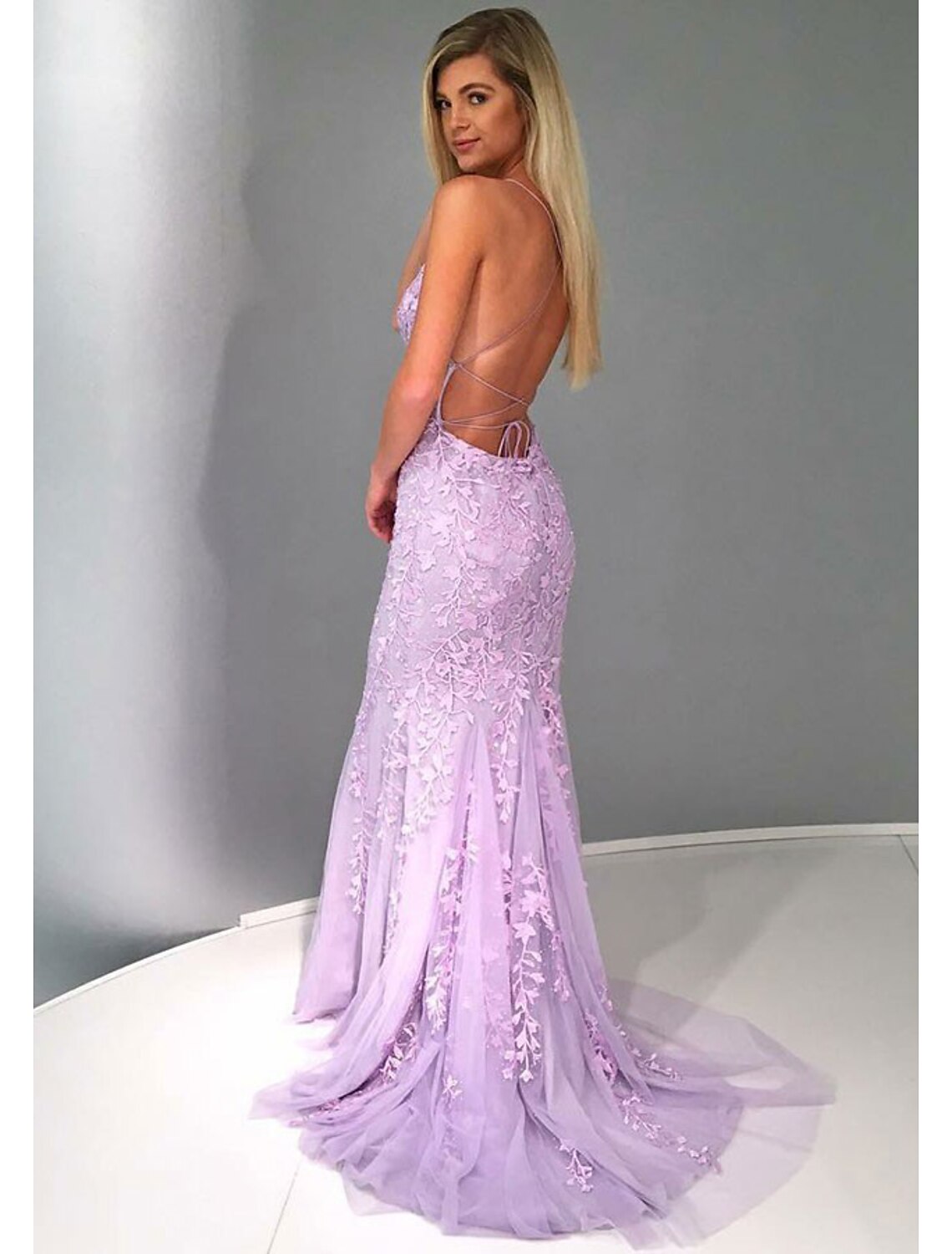 Back view of a strapless mermaid trumpet prom dress showing lace details and court train.