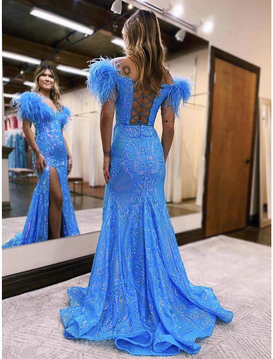 Back view of a navy blue sequined mermaid trumpet dress with a high slit.