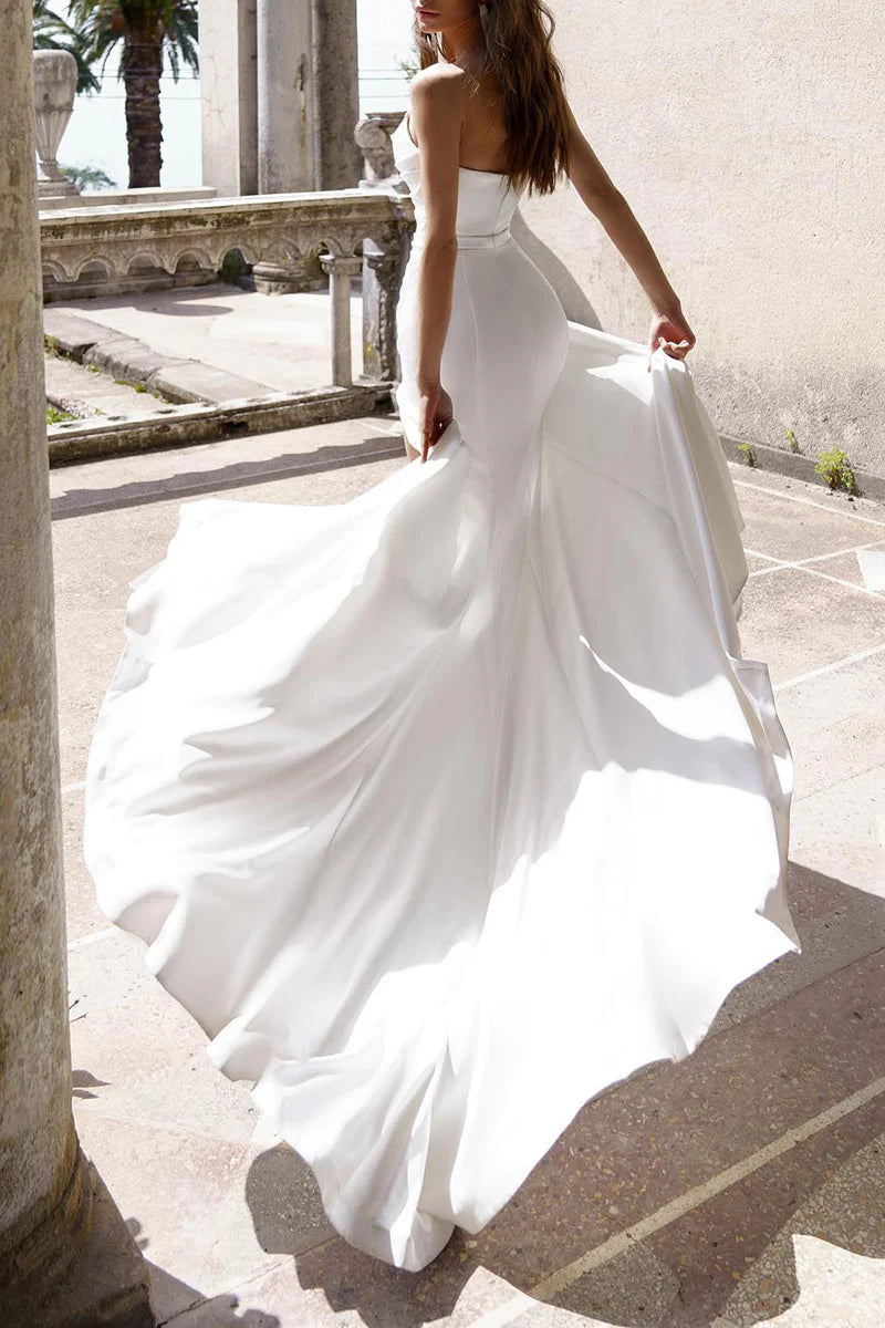Side view of a bride wearing a white satin mermaid trumpet wedding gown with a V-neck.