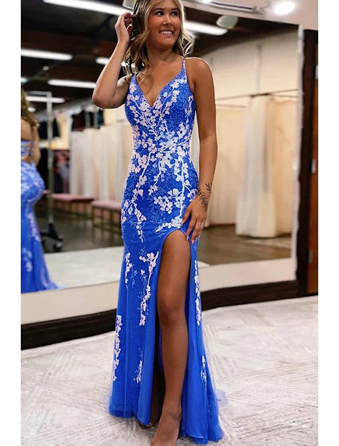 Model wearing an elegant V-neck mermaid trumpet prom dress with appliques and a front slit.