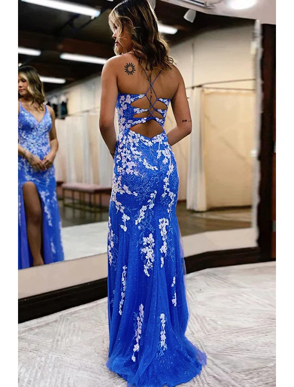 Side view of a model in a sleeveless tulle mermaid prom dress with a sweep train.