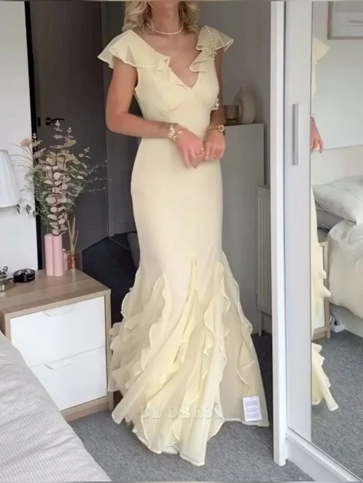 Woman wearing an elegant mermaid V-neck backless chiffon formal gown.