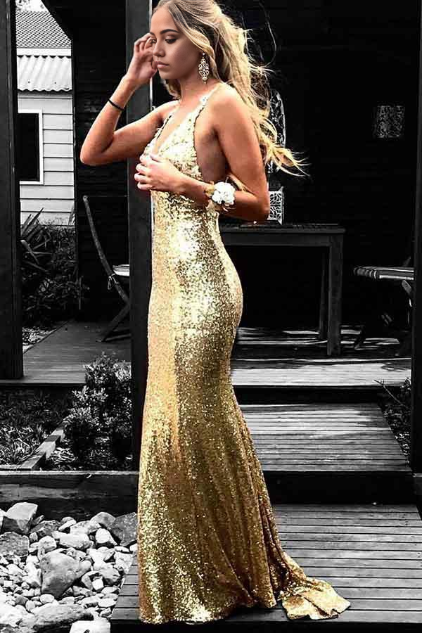 Model wearing a gold sequined mermaid prom dress with V-neck and appliques.
