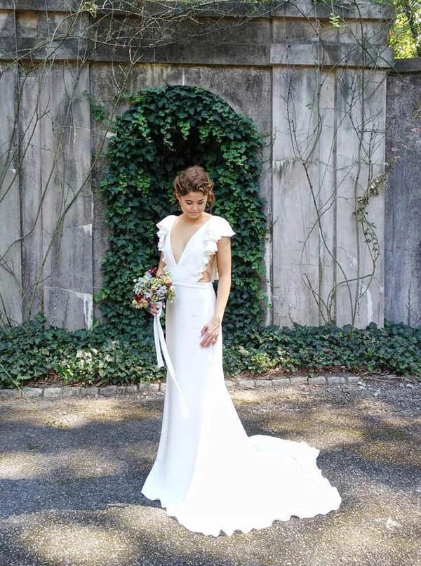 Elegant mermaid wedding dress with V-neck, cap sleeves, and ruffled skirt.