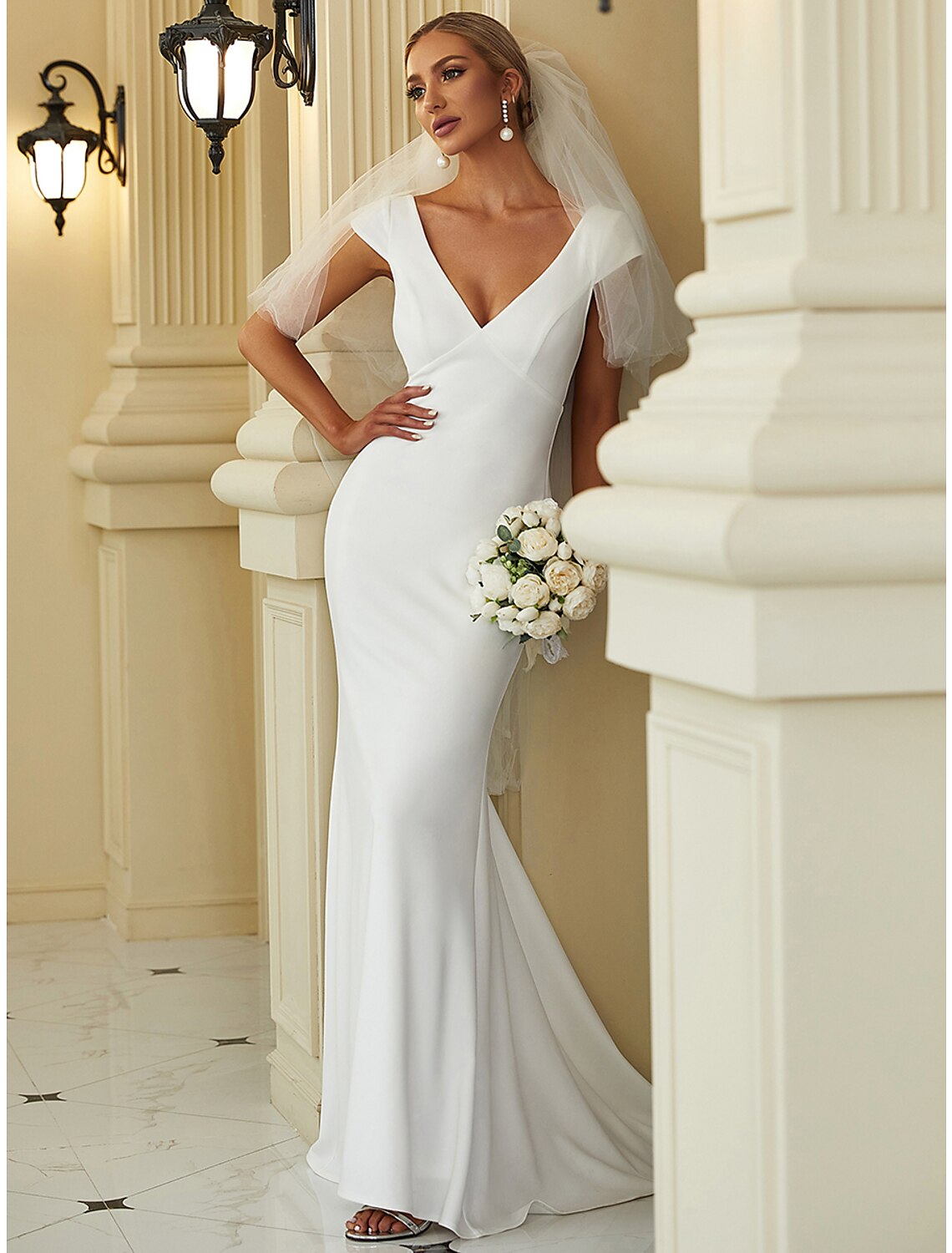 Side view of a bride in a white V-neck cap sleeve mermaid gown.