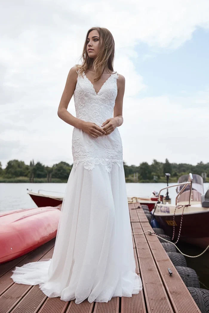 Elegant mermaid wedding dress with lace bodice, V-neck, and flowing tulle court train.