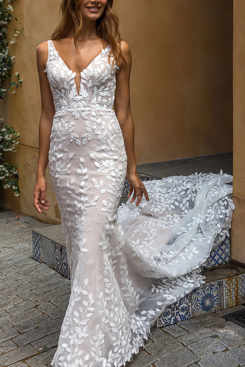 Full view of a woman wearing an elegant mermaid V-neck lace wedding dress.