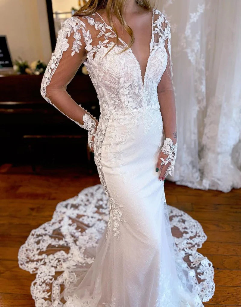 Side view of a mermaid V-neck long sleeve wedding dress, showcasing appliques and train.