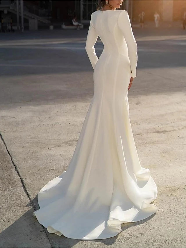 Back view of a model in a white mermaid V-neck long sleeve wedding dress.