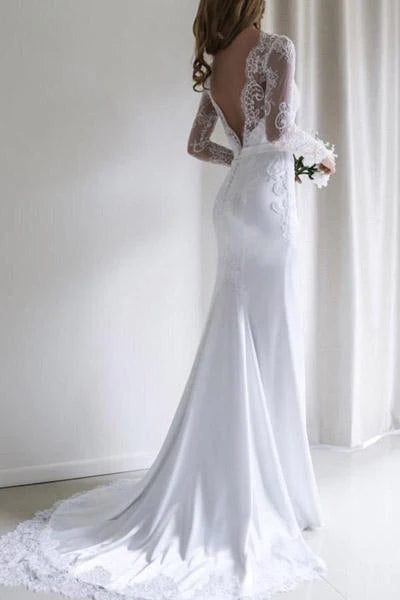 Side view of a bride wearing a mermaid wedding gown, highlighting the long lace sleeves and dramatic train.