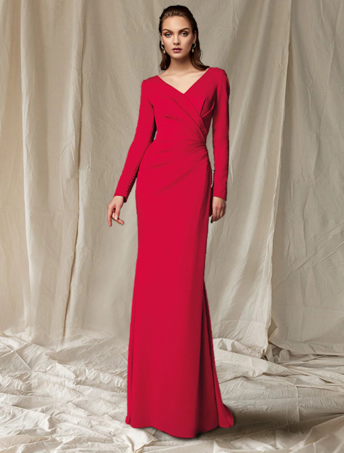 Woman wearing an elegant mermaid V-neck long sleeve Mother of the Bride dress with side draping.