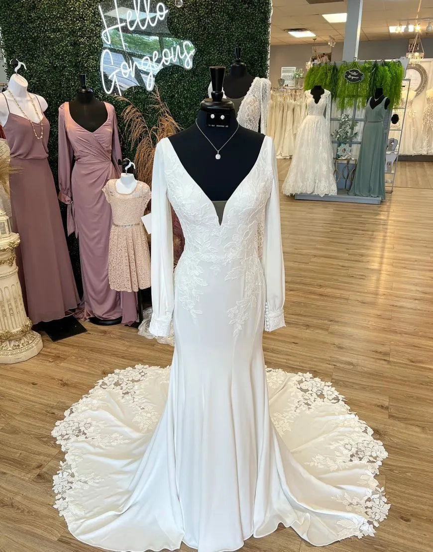 Front view of an elegant mermaid V-neck long sleeve wedding dress with appliques and a court train.