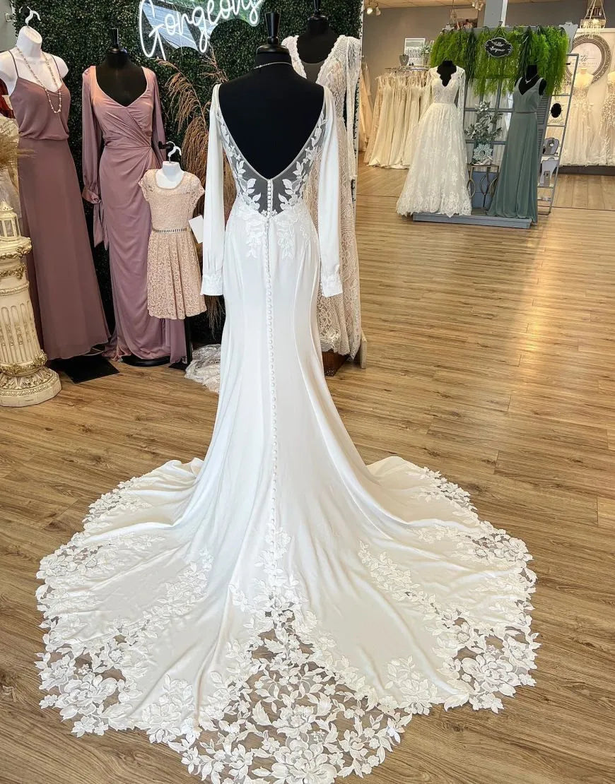 Side view of a mermaid V-neck long sleeve wedding dress, showcasing appliques and the flowing train.