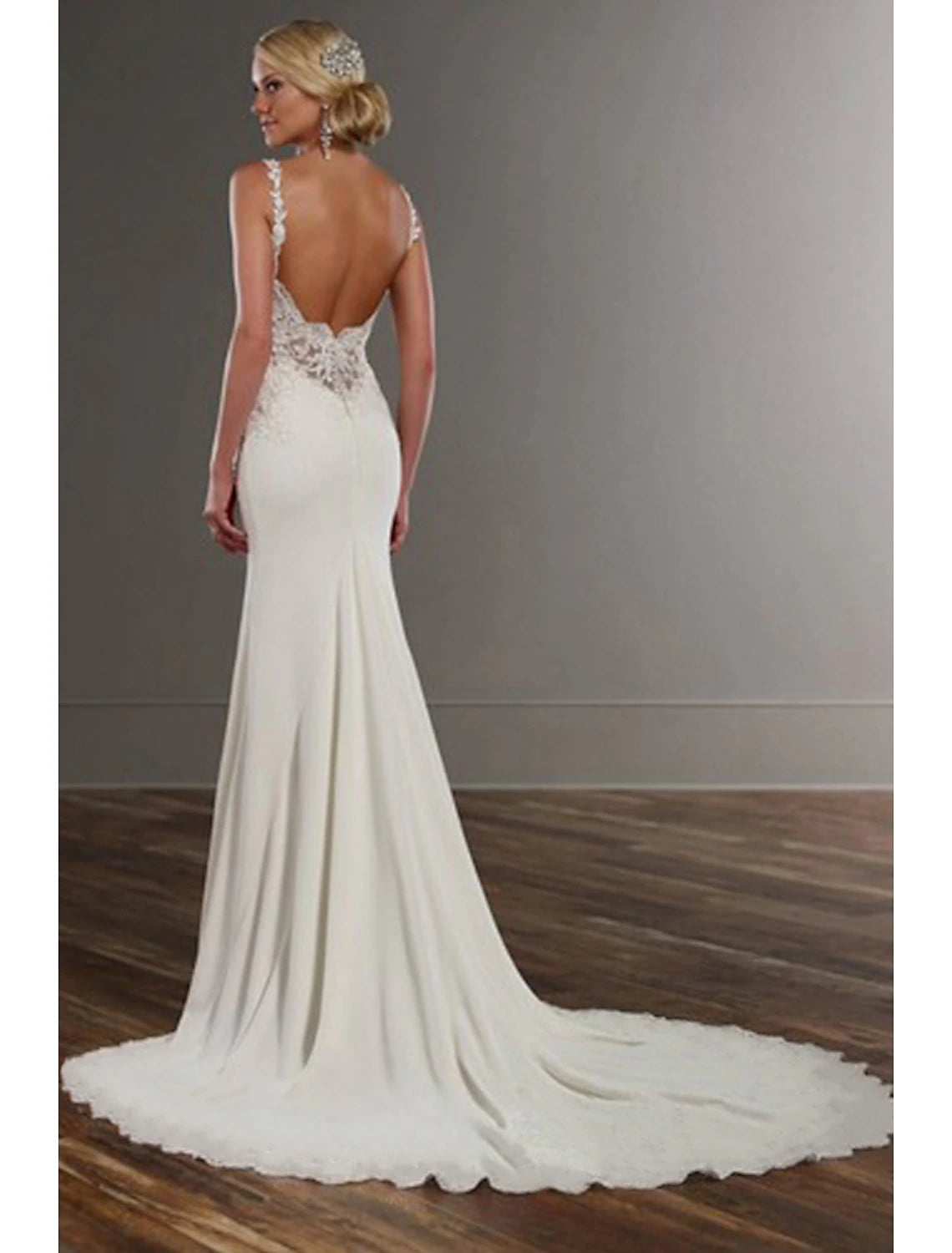 Back view of a white bridal gown showing open back and chapel train.