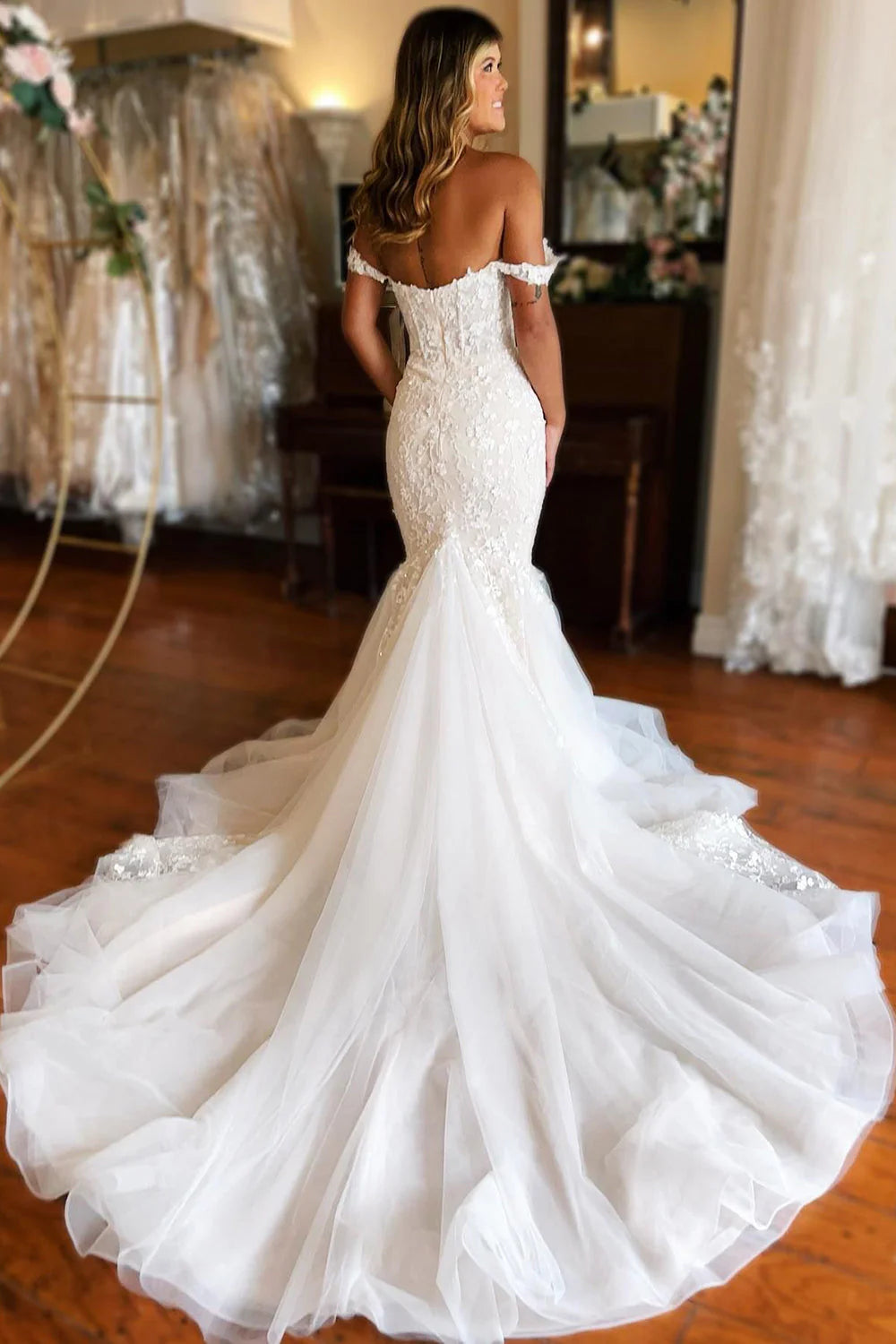 Back view of a white mermaid wedding dress showing lace details and train.