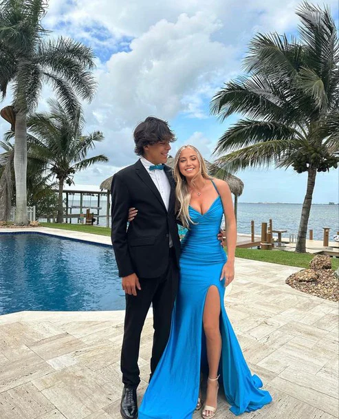 Woman wearing an elegant blue mermaid V-neck prom dress with spaghetti straps and a thigh-high split.