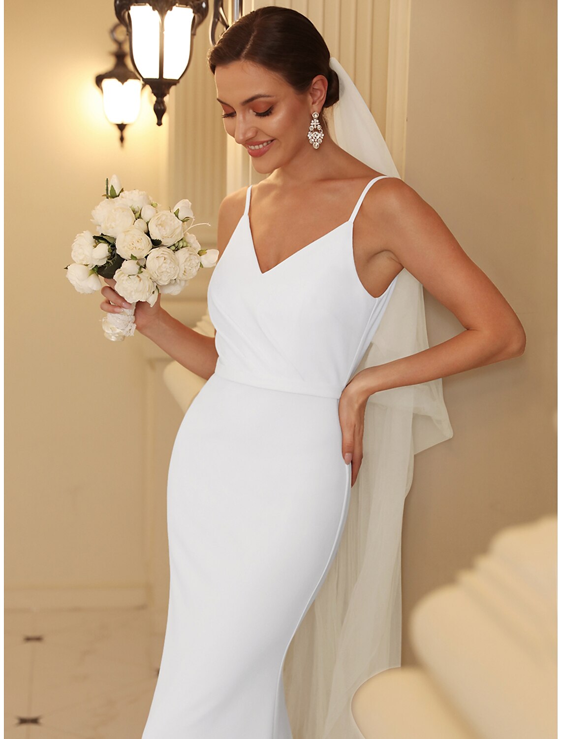 Back view of a mermaid trumpet bridal gown with a sweep train and ruched details.