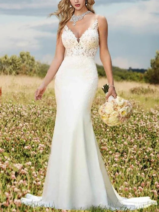 A bride wearing an elegant white mermaid V-neck wedding dress with intricate appliques and a flowing court train.