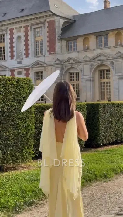 Back view of a flowing yellow chiffon mermaid dress, showcasing its elegant train.