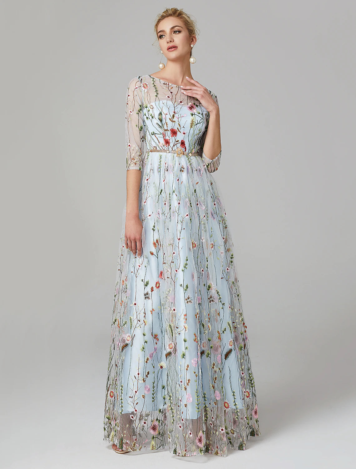 Woman wearing an elegant navy A-line floral lace evening gown with 3/4 illusion sleeves.