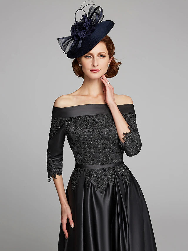 Woman posing gracefully in the navy off-shoulder satin lace Mother of the Bride dress.