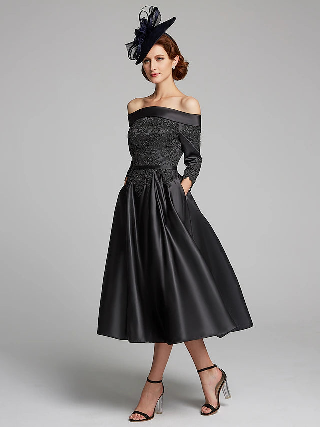 Full length view of the elegant navy A-line tea-length dress with a lace sash.