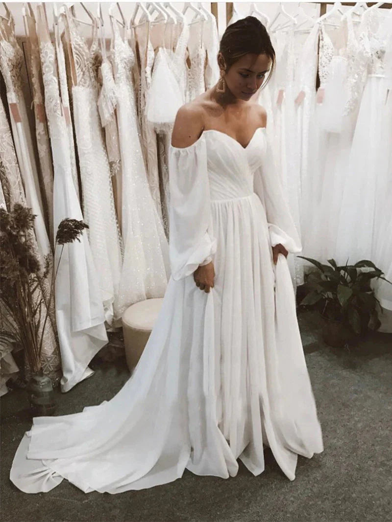 Close-up of the off-shoulder neckline and long sleeves on a chiffon wedding dress.