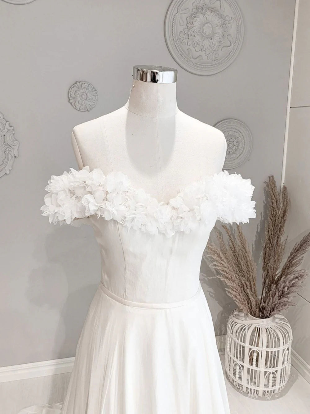 Side view of a white off-shoulder floral long beach wedding dress with flowing skirt.