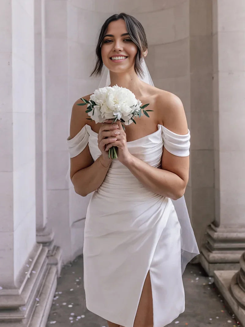 Model wearing a short off-shoulder satin cowl neck dress with a slit, front view.