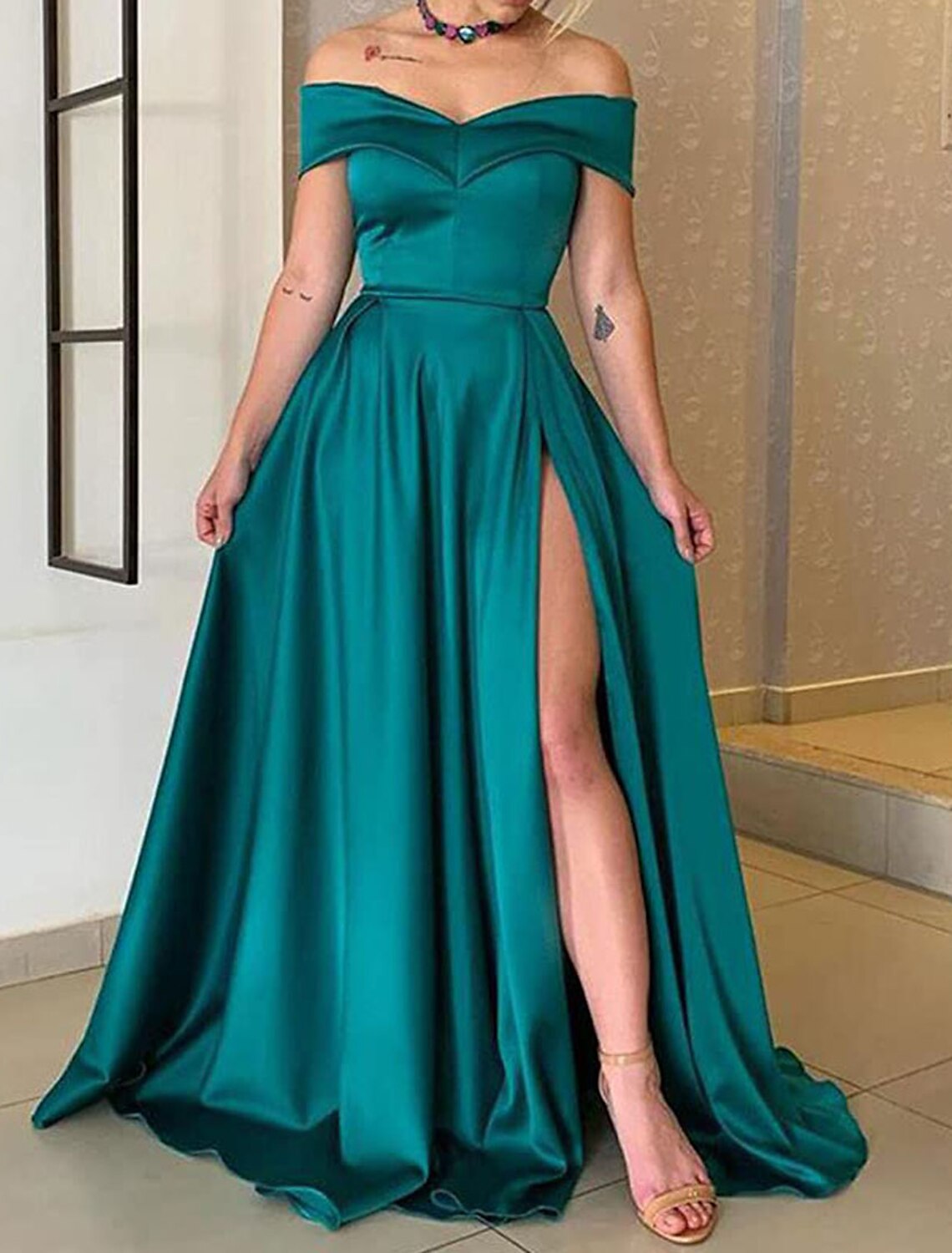 Back view of the long off-shoulder satin gown, highlighting its flowing A-line silhouette.