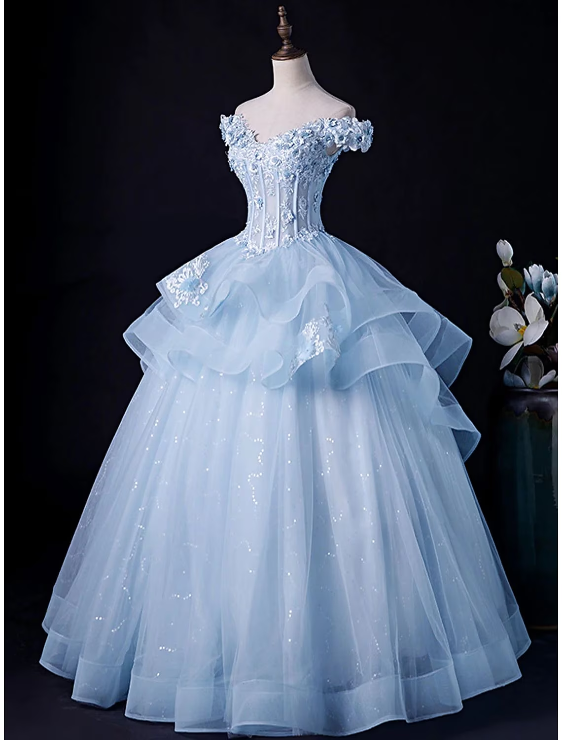 Close-up of pleated tulle fabric and appliques on a formal gown.