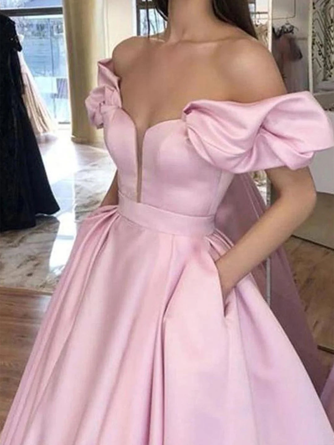 Model wearing an elegant off-shoulder floor-length ball gown in a formal setting.