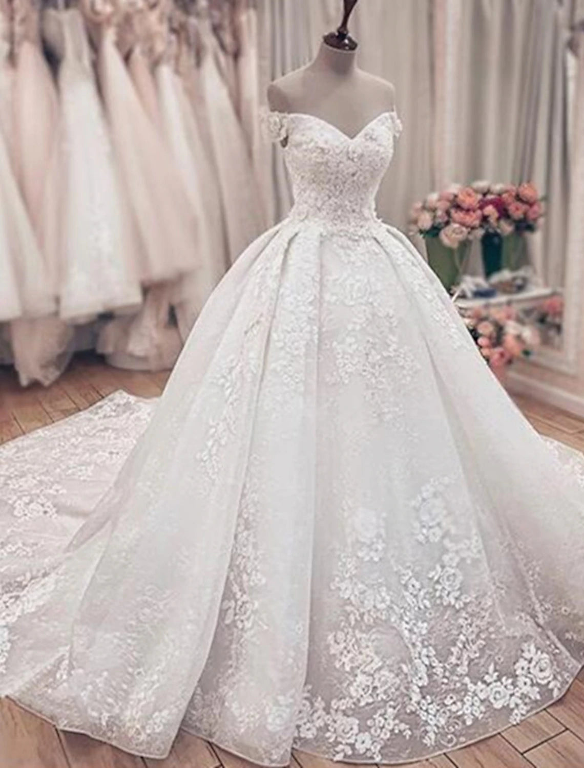 Elegant off-shoulder ball gown wedding dress with lace appliques and cap sleeves.