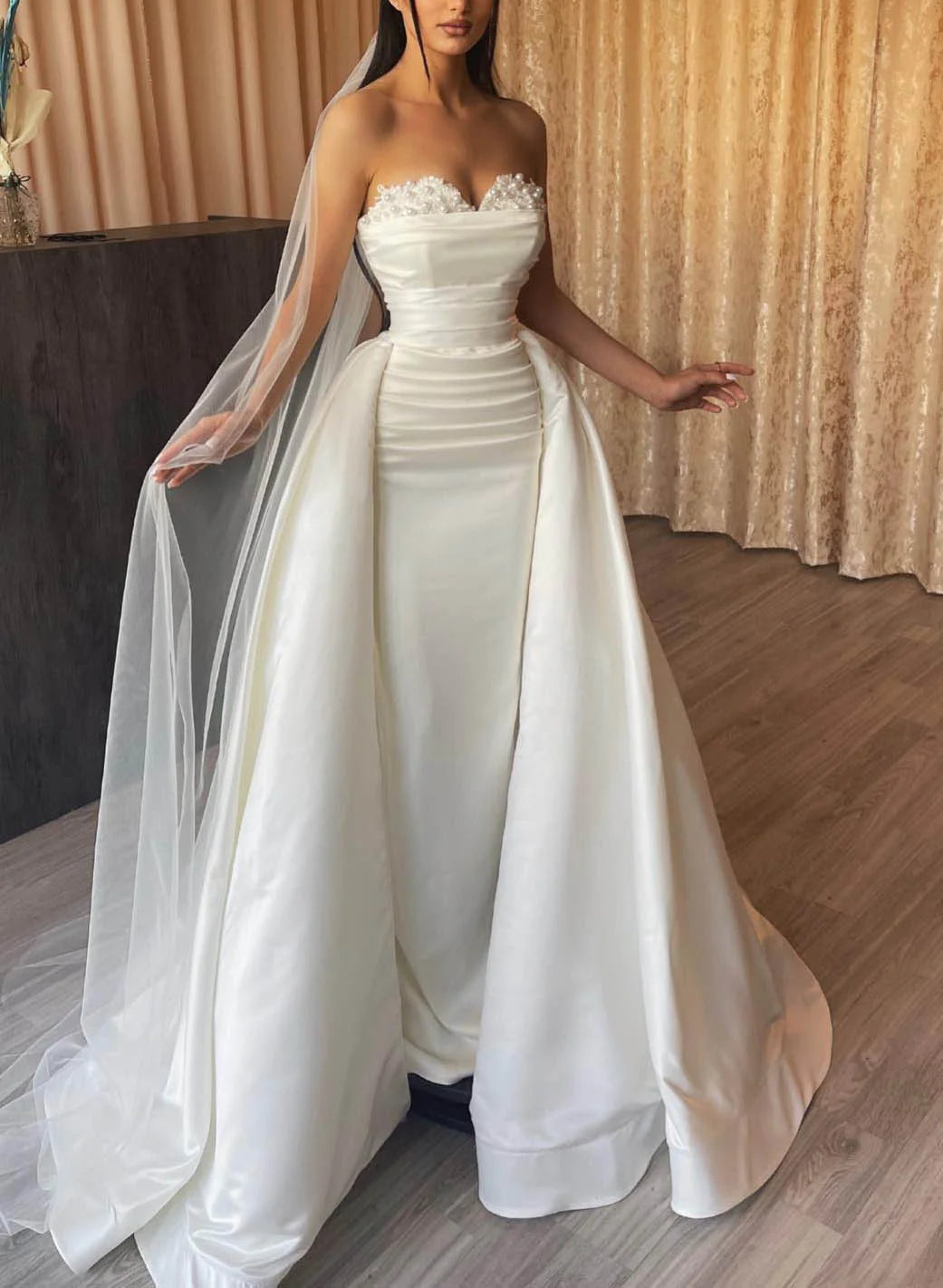 Model wearing an elegant off-shoulder lace sheath wedding dress.