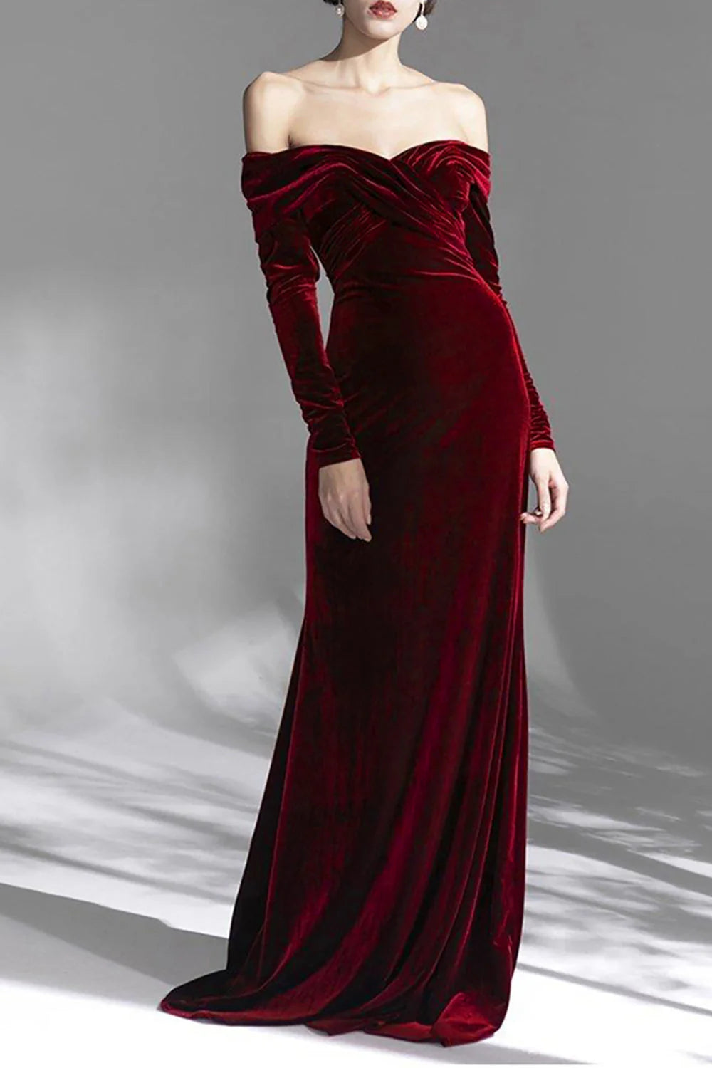 Woman wearing an elegant burgundy off-shoulder long sleeve floor-length prom dress, posing gracefully.