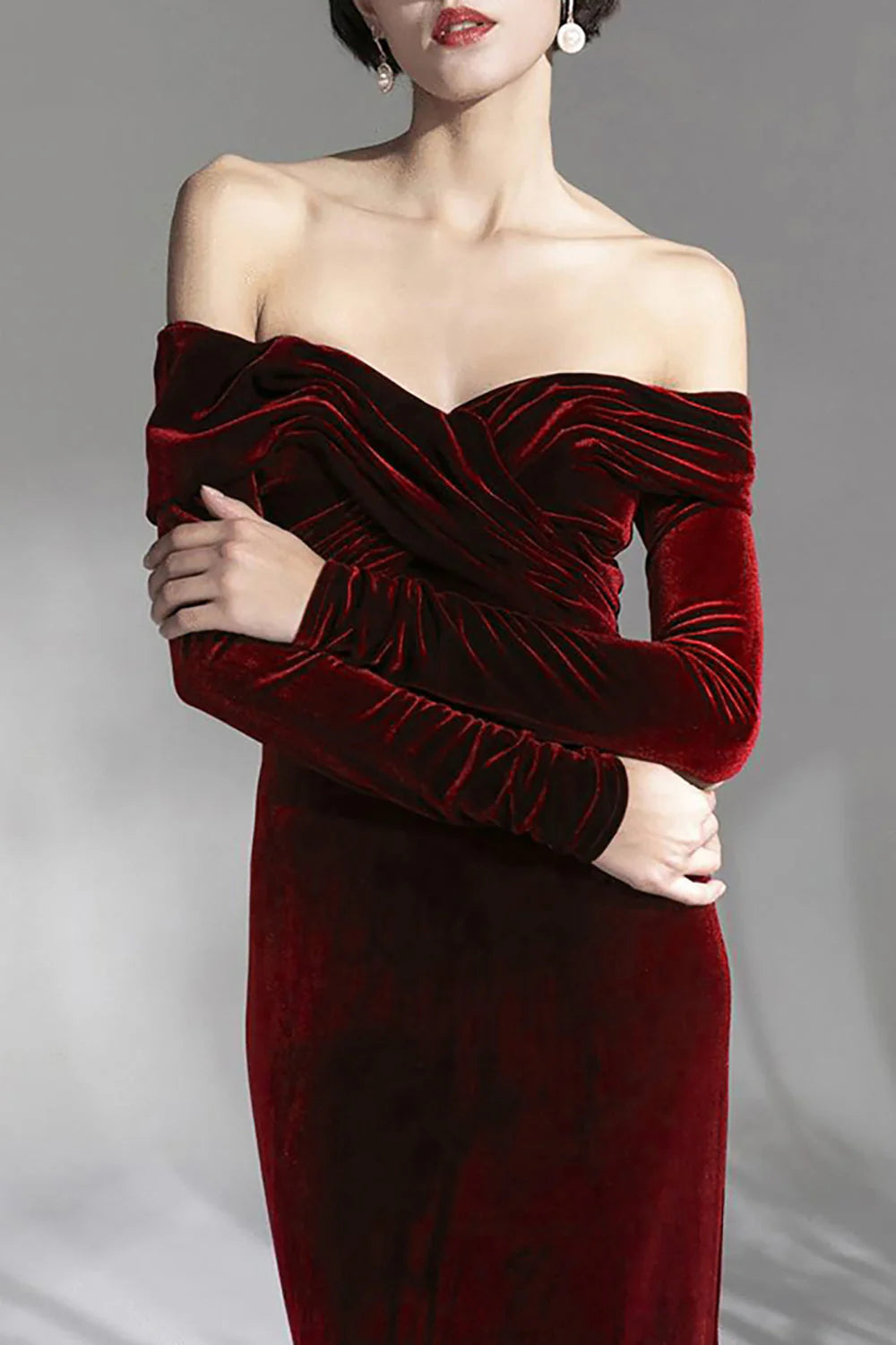 Side profile of a woman in a sophisticated burgundy off-shoulder long sleeve evening dress.