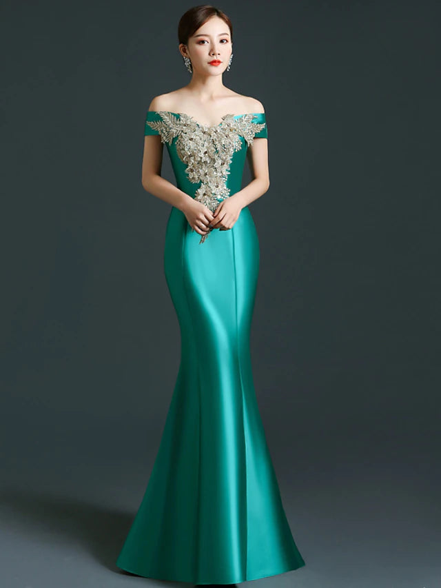 Elegant off-shoulder satin mermaid gown with appliques, worn by a woman.