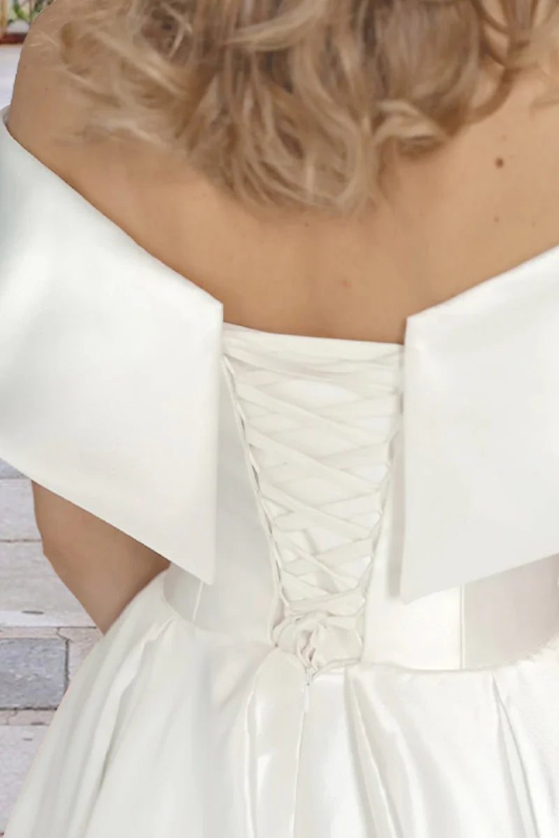 Off-shoulder satin tea length wedding dress, ideal for a beach ceremony, side view.