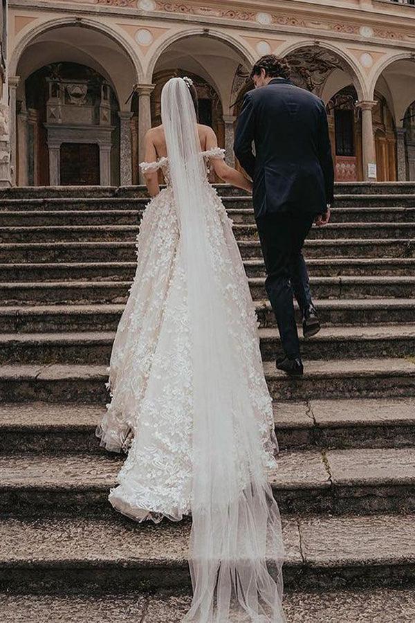 Full view of off-shoulder lace tulle wedding dress with flowing skirt.