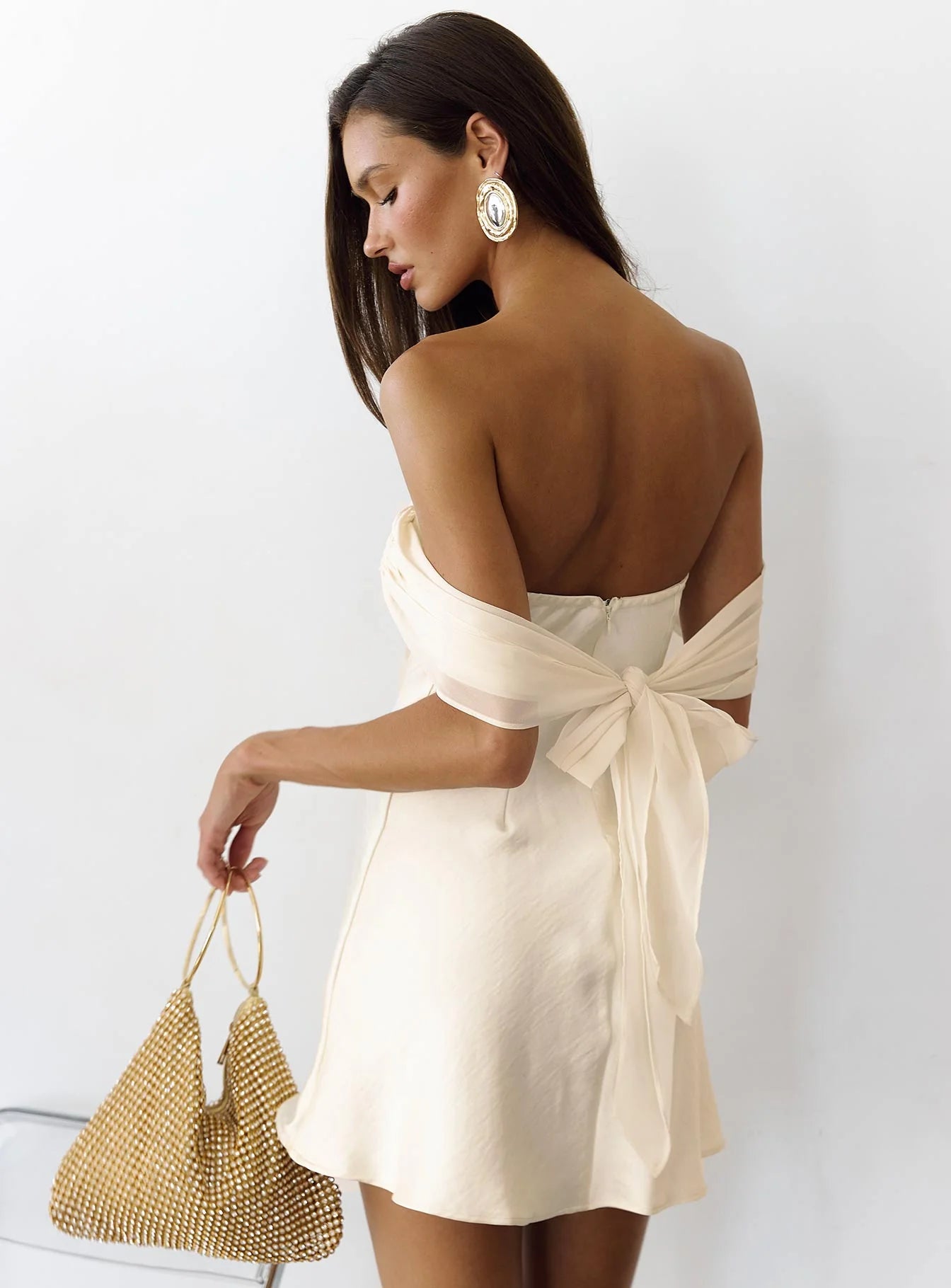 Back view of the cream ivory off-shoulder satin mini dress showing the tie-back detail.