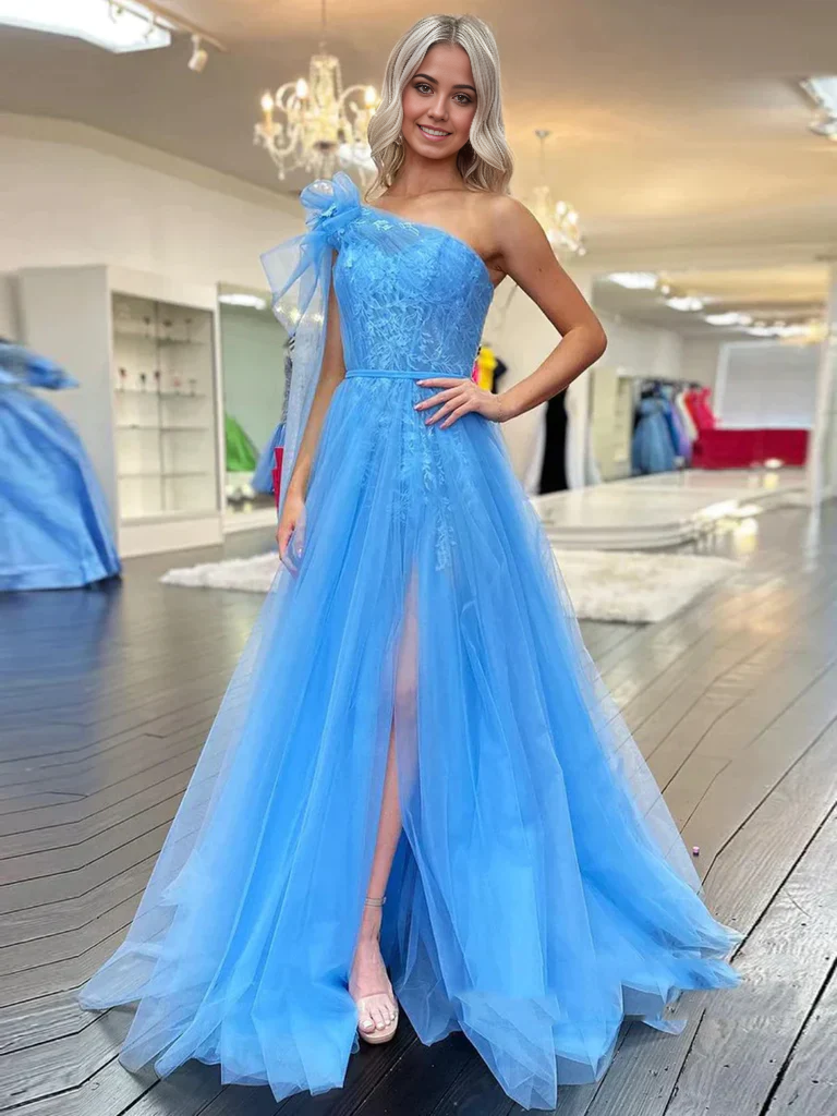 Woman posing in an elegant one-shoulder lace prom dress with a high slit.