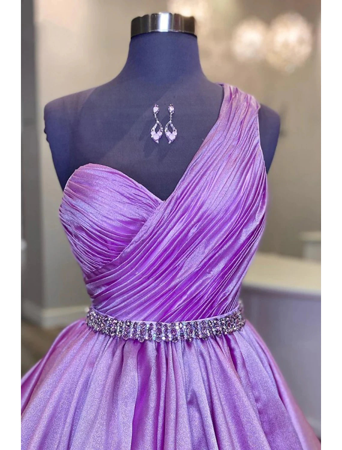 Close-up of the one-shoulder design and ruched crystal embellishments on the ball gown.