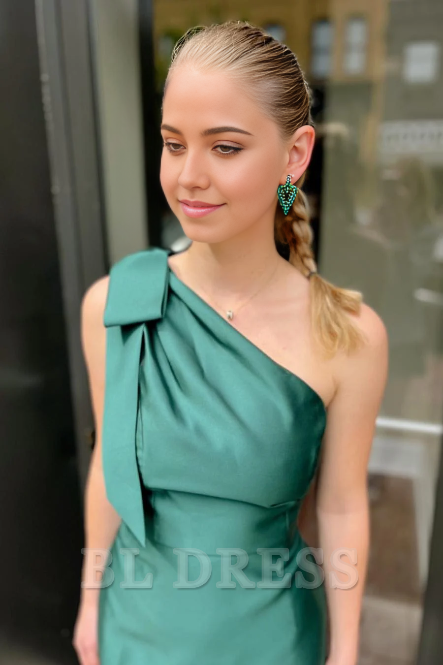 Long green satin evening gown featuring a one-shoulder design and pleated skirt.