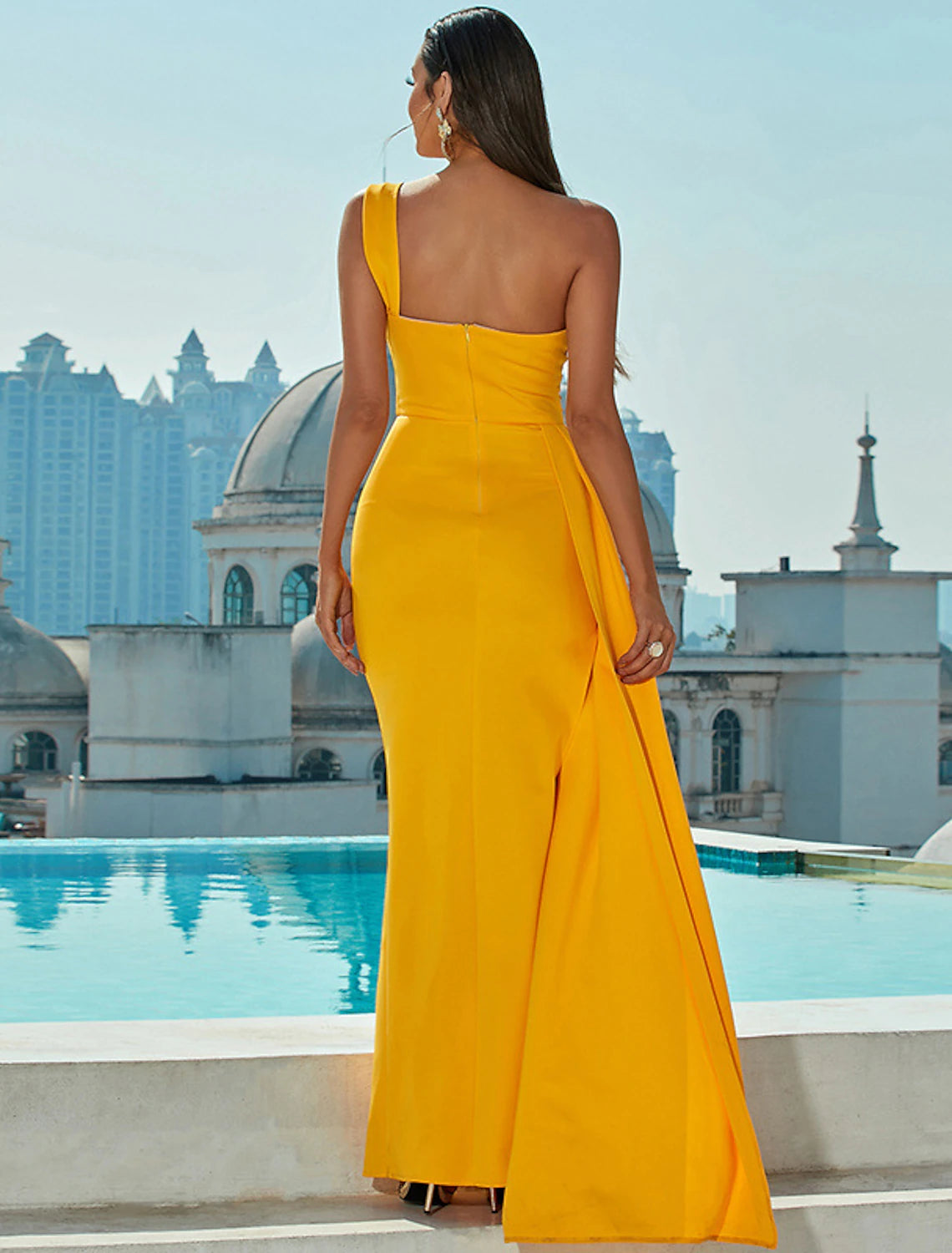 Woman posing in a dark blue one-shoulder mermaid trumpet gown, showing the full silhouette.